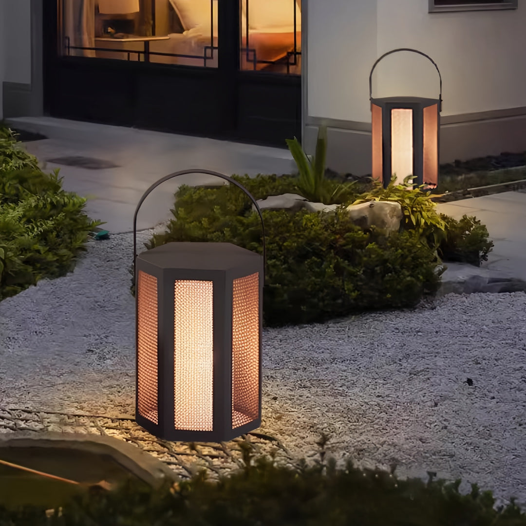Multiple outdoor lighting lanterns illuminating a landscaped garden pathway with soft warm light.