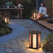 Outdoor lighting lanterns positioned around a garden seating area, producing cozy evening atmosphere.