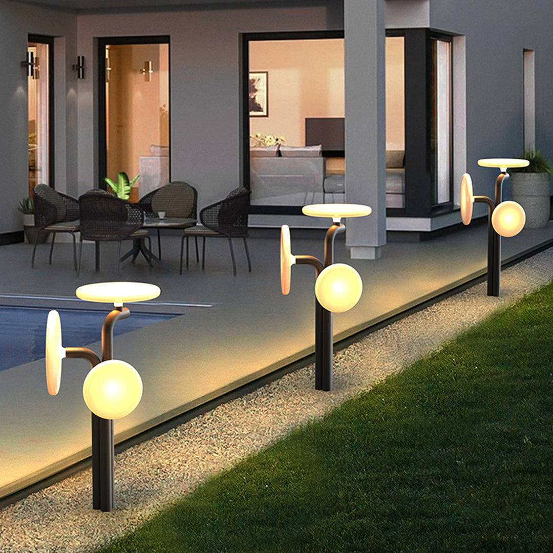 Rendered outdoor scene showing multiple outdoor lighting path lights illuminating a walkway near a house.