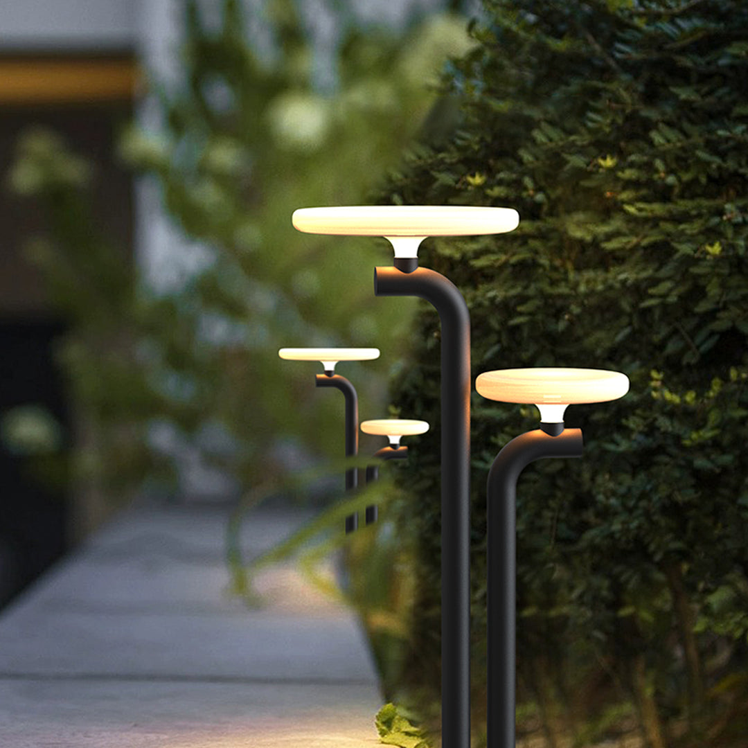 Outdoor lighting path lights installed along landscaped greenery with warm ambient glow.