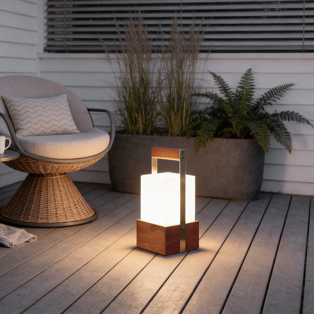 Outdoor lights lanterns with a modern wooden design, placed on a patio beside a wicker chair.