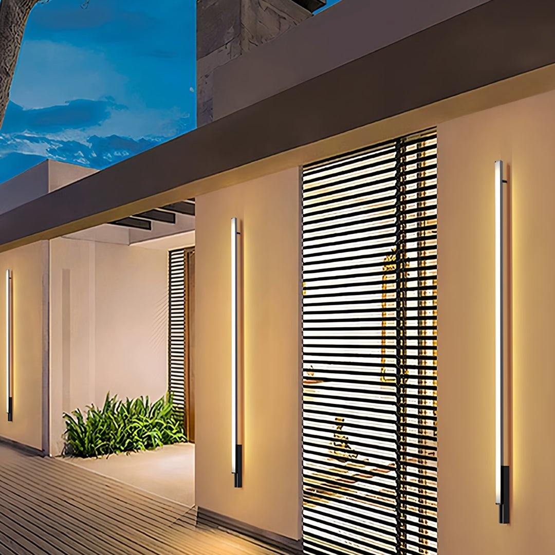 Warm linear outdoor lights wall sconces highlighting the façade of a modern home at dusk.