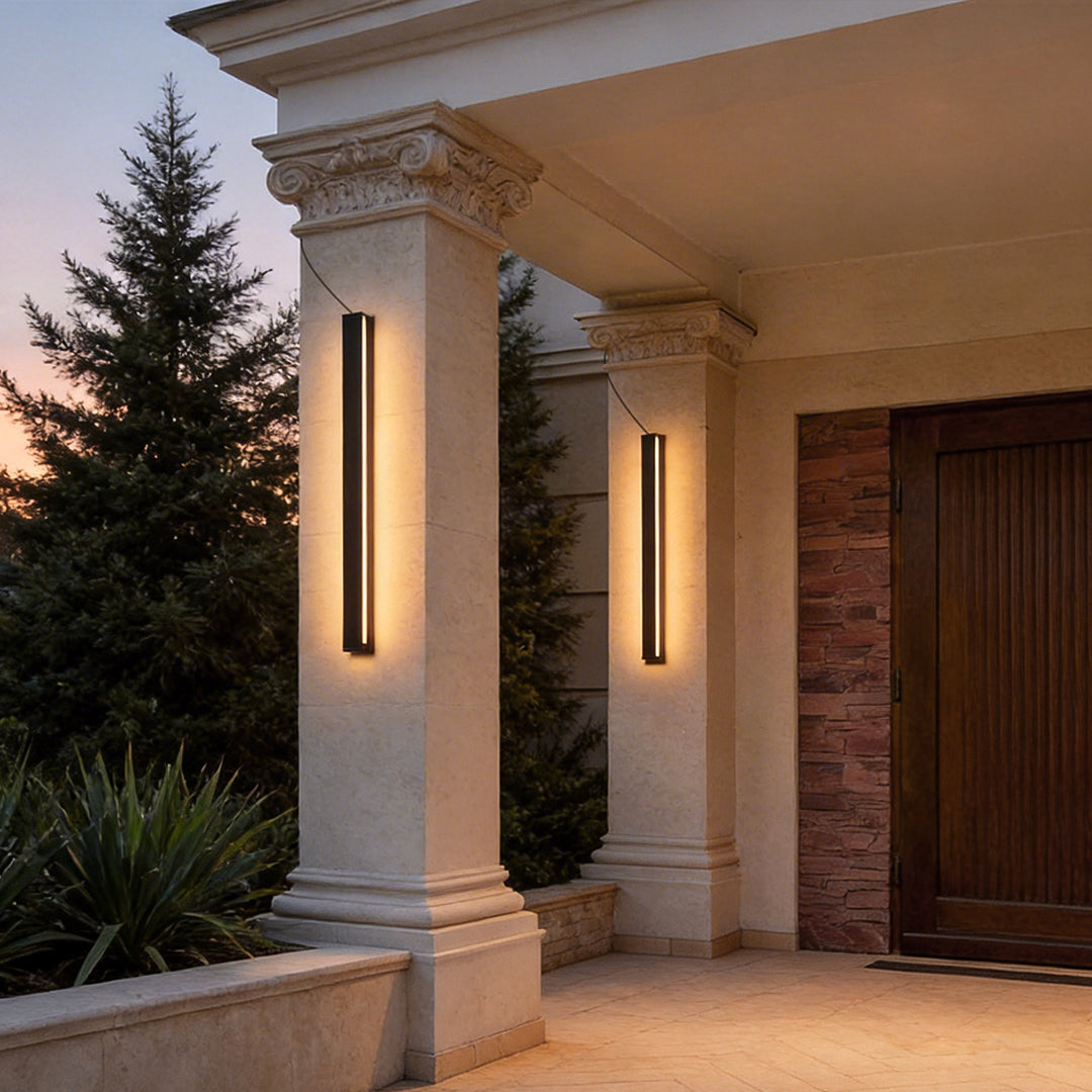 Outdoor linear wall light mounted on classical porch columns creating elegant entrance lighting at dusk.