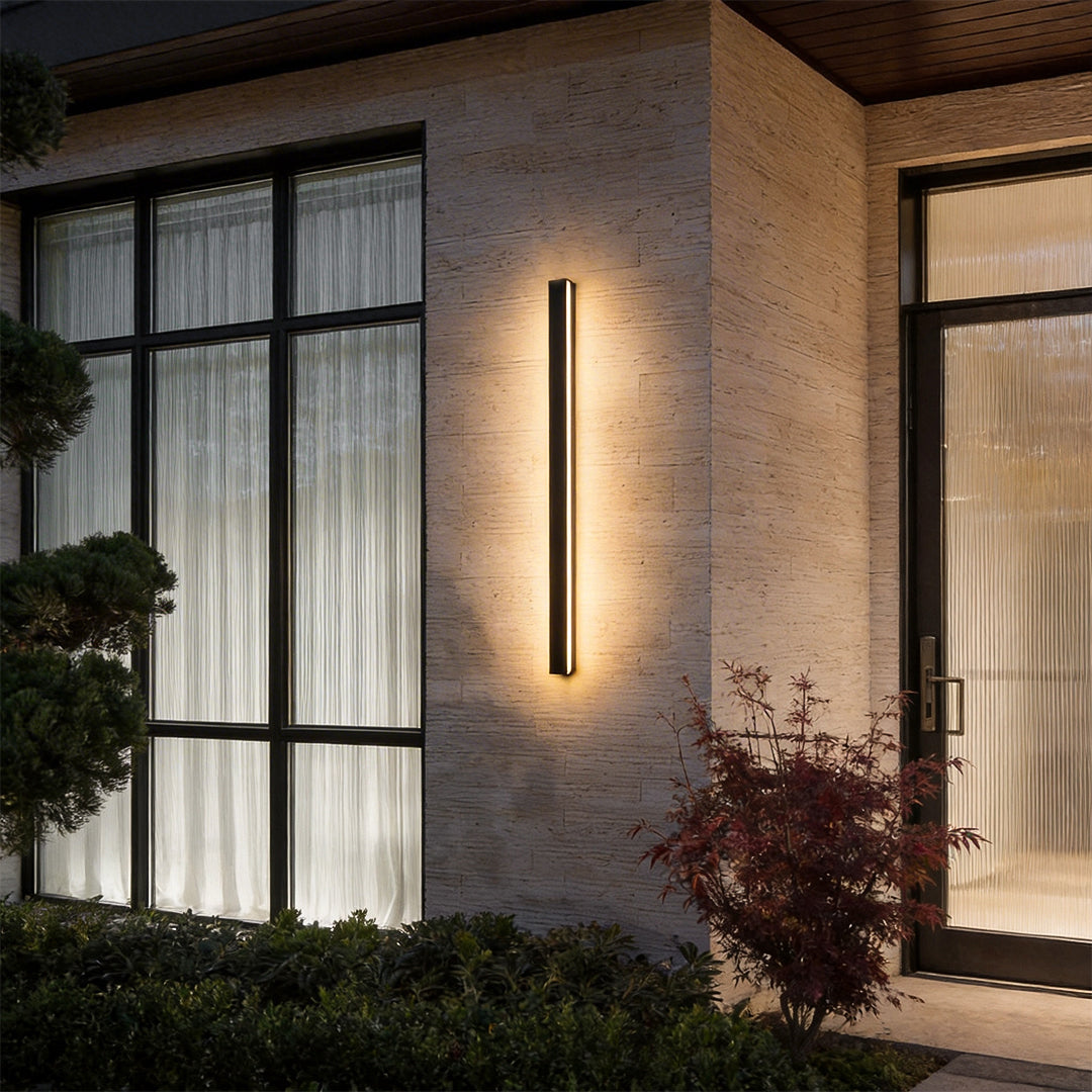 Outdoor linear wall light installed beside a modern window facade providing warm architectural lighting.