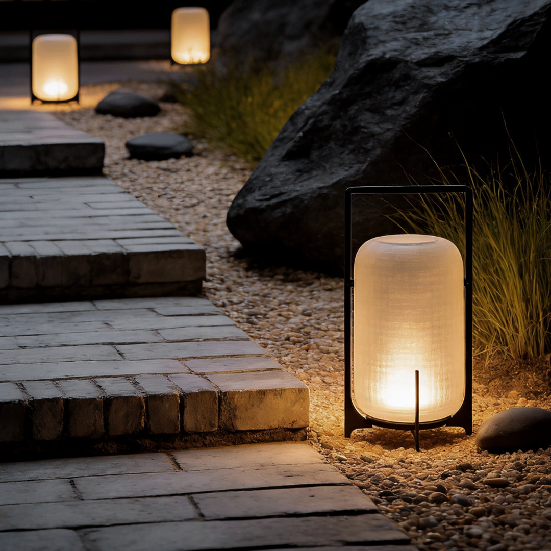 Outdoor modern handle lantern lighting up garden pathway with warm glow and natural stone steps.