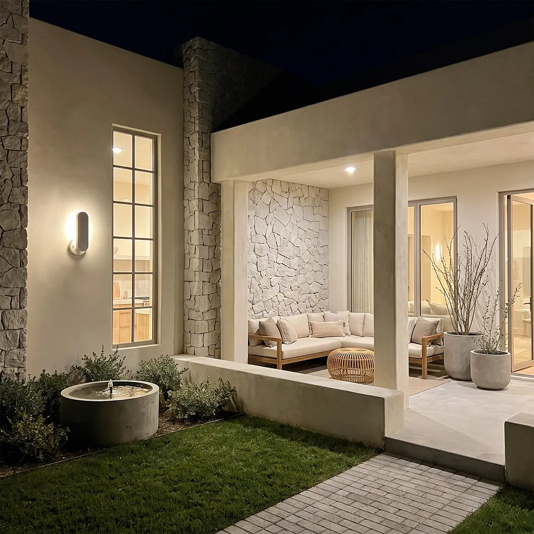 Outdoor modern wall lighting mounted on a contemporary home exterior beside large windows and a landscaped courtyard