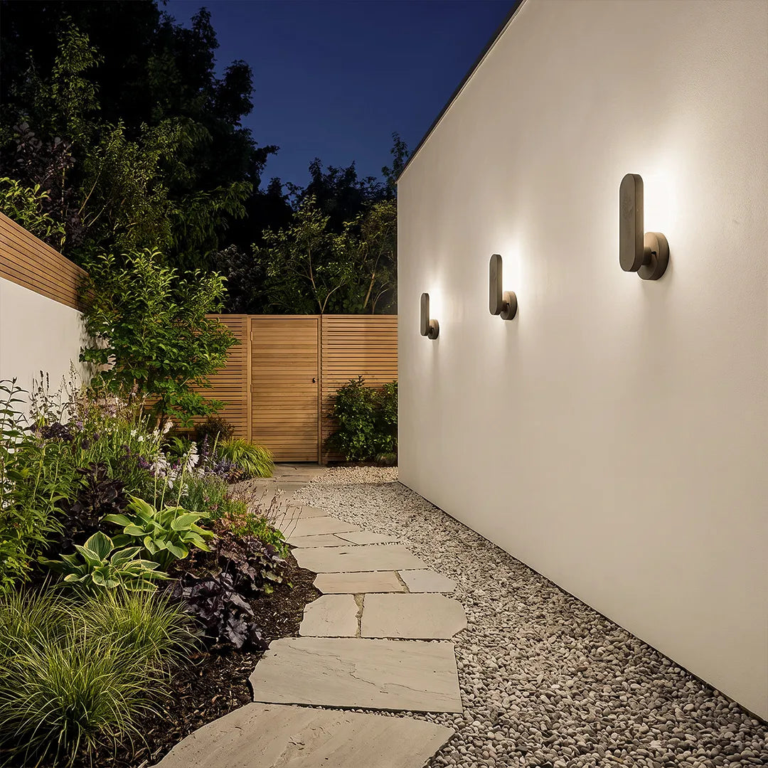 Outdoor modern wall lighting illuminating a minimalist garden walkway beside a white exterior wall at night.