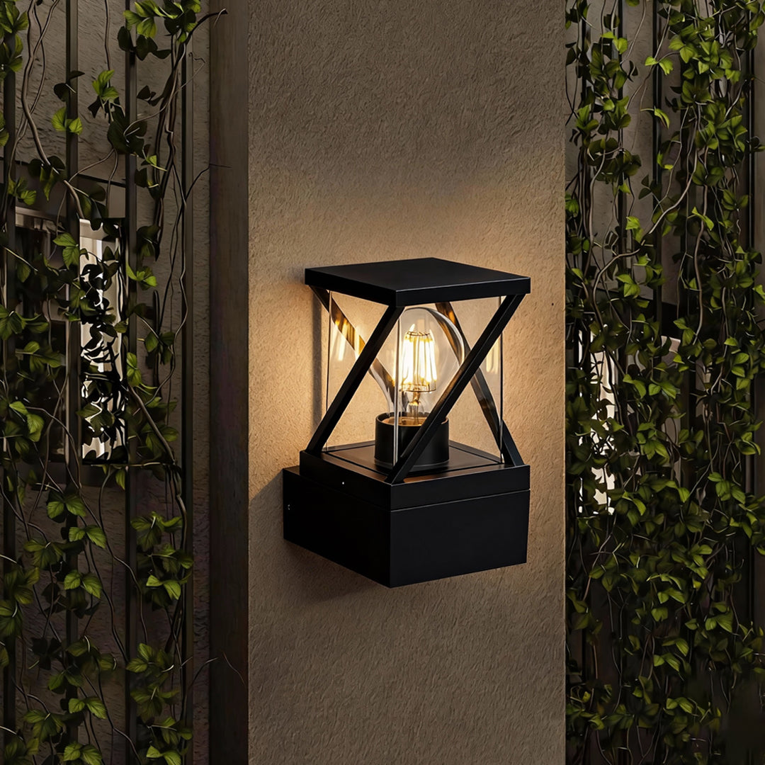 Outdoor modern wall sconce illuminating a textured exterior wall, with black metal frame and warm interior bulb.
