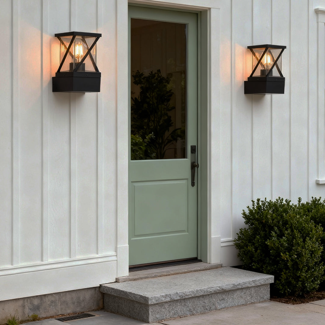 Outdoor modern wall sconce installed beside a white door, creating welcoming warm lighting with sleek lantern design.