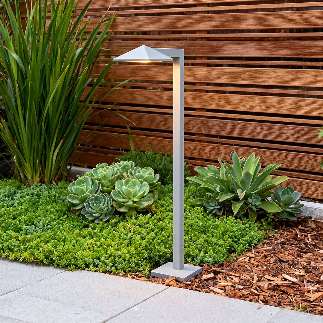 Outdoor pathway light in a garden with lush plants, adding a contemporary touch to the outdoor space.