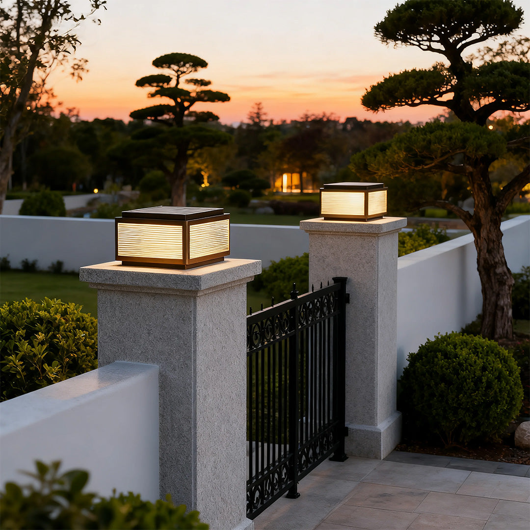 Outdoor patio pillar light in a garden with a fence, adding a contemporary touch to the outdoor space.