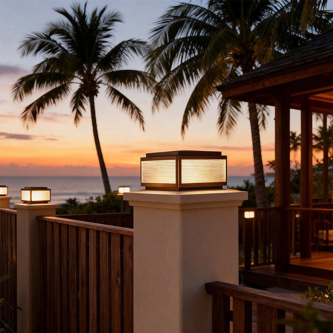 Outdoor patio pillar light in a garden with a fence, adding a contemporary touch to the outdoor space.