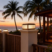 Outdoor patio pillar light in a garden with a fence, adding a contemporary touch to the outdoor space.