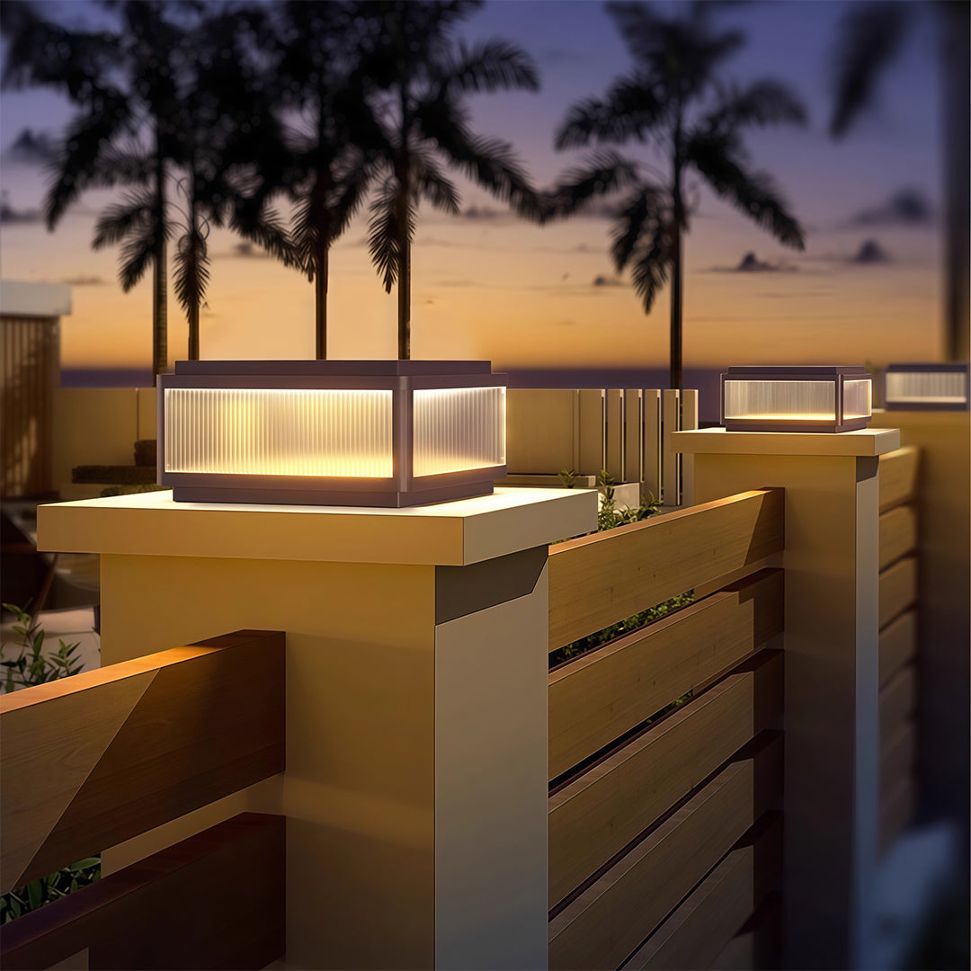 Outdoor patio pillar light in a garden with a fence, adding a contemporary touch to the outdoor space.