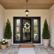 Outdoor pendant lighting fixtures hanging above a front entry with black double doors and a warm wood ceiling.