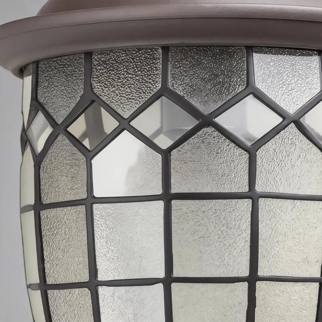 Close-up of outdoor pendant lighting fixtures featuring a geometric metal frame and textured glass panels.