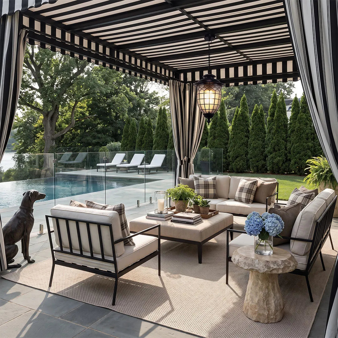 Outdoor pendant lighting fixtures lighting a covered pergola lounge with cushioned seating and garden views.