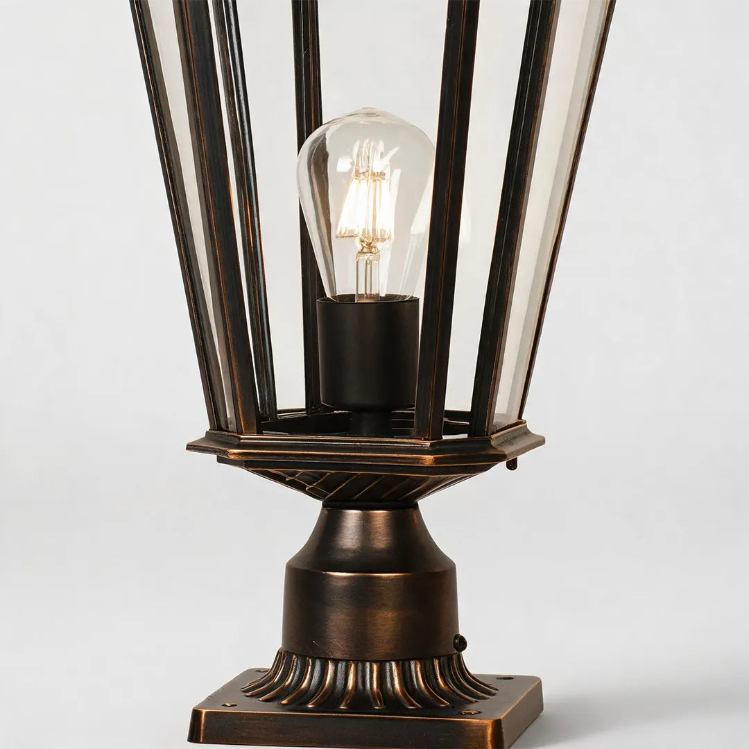 Outdoor pillar light fixtures close-up featuring the exposed bulb, tapered glass panels, and bronze base design.