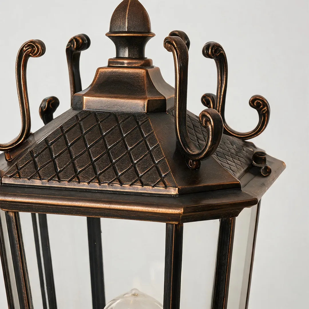 Outdoor pillar light fixtures detail showing the decorative bronze lantern top with curled metal accents and textured finish.
