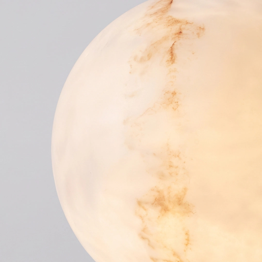 Close-up of the glowing marble-look globe shade on outdoor pillar lights.