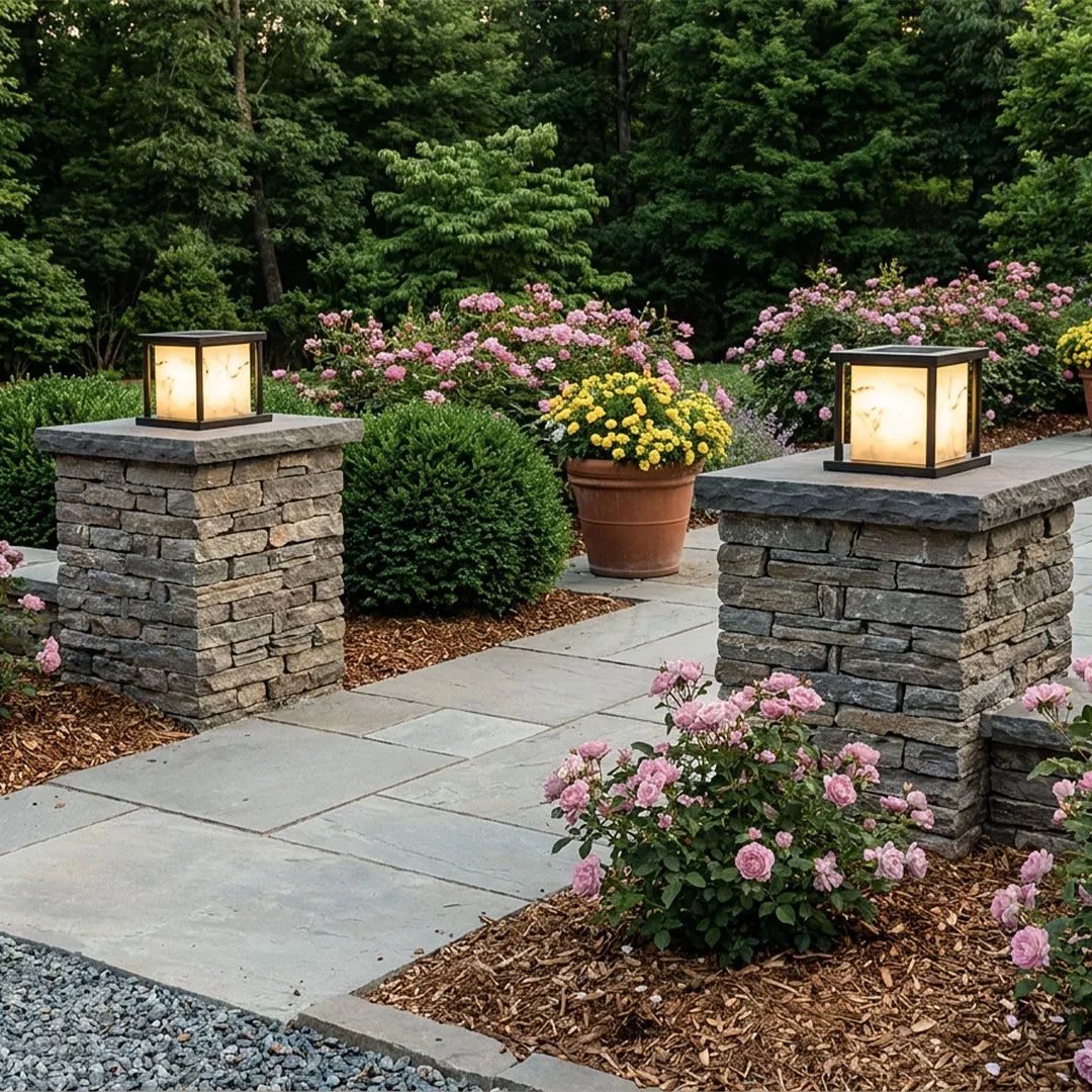 Outdoor pillar solar lights installed on landscape pillars beside a driveway entrance.