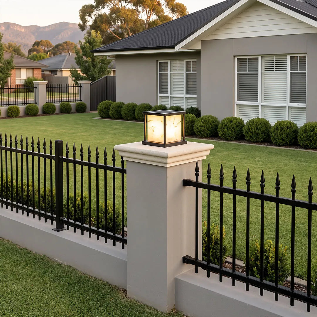 Outdoor pillar solar lights mounted on a fence pillar with a warm illuminated diffuser.