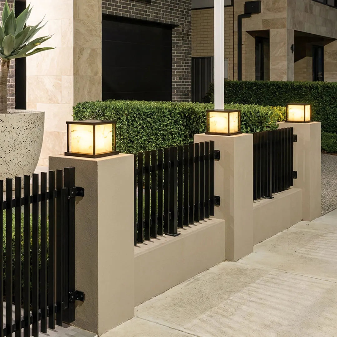 Outdoor pillar solar lights mounted on fence columns with warm architectural lighting.
