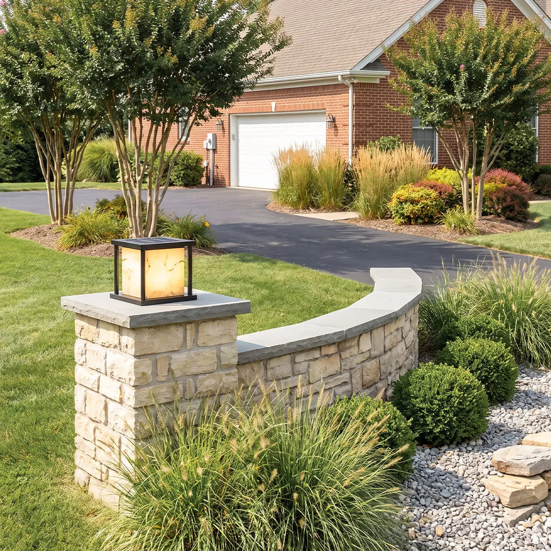 Outdoor pillar solar lights installed on stone pillars in a landscaped front yard.