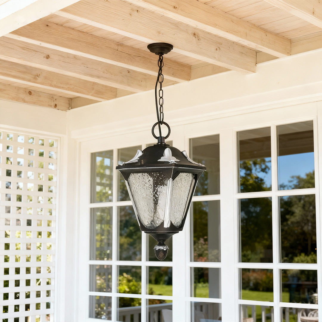 Outdoor porch pendant light illuminating exposed beam ceiling near white trellis and French doors