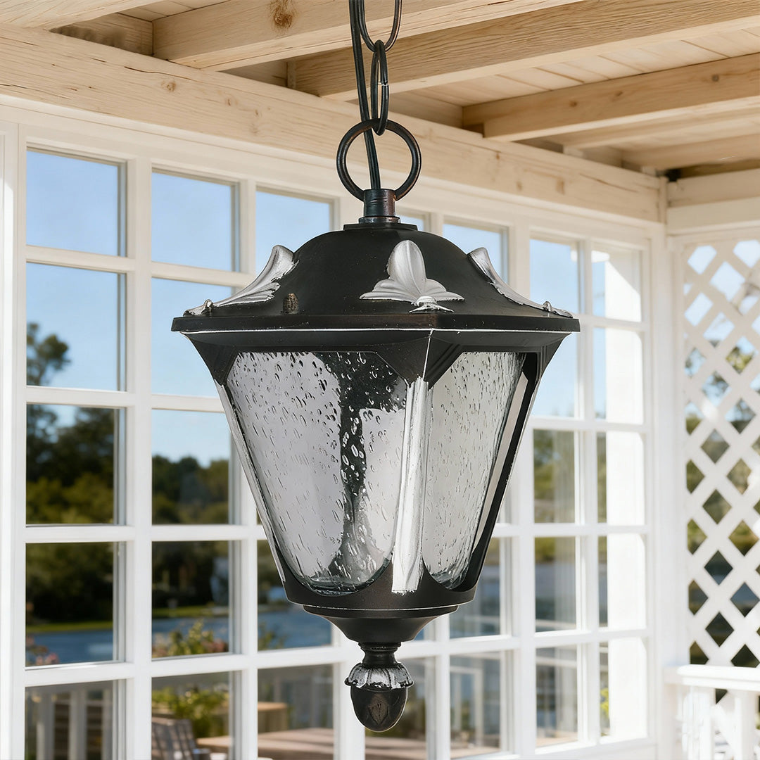 Outdoor porch pendant light hanging from natural wood ceiling with lattice detail and garden view