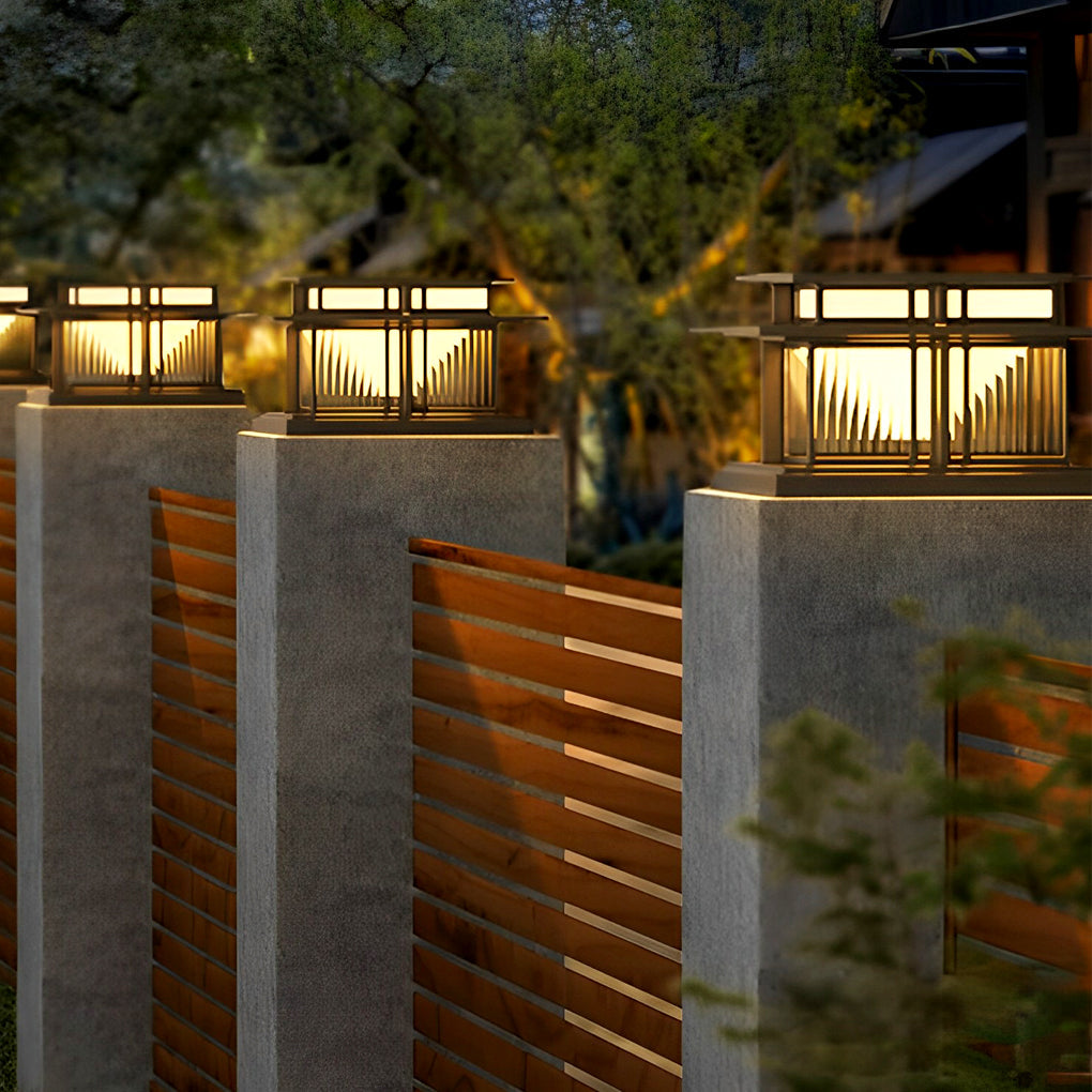 Outdoor porch pillar lights lining a wooden fence, creating warm pathway lighting at night.
