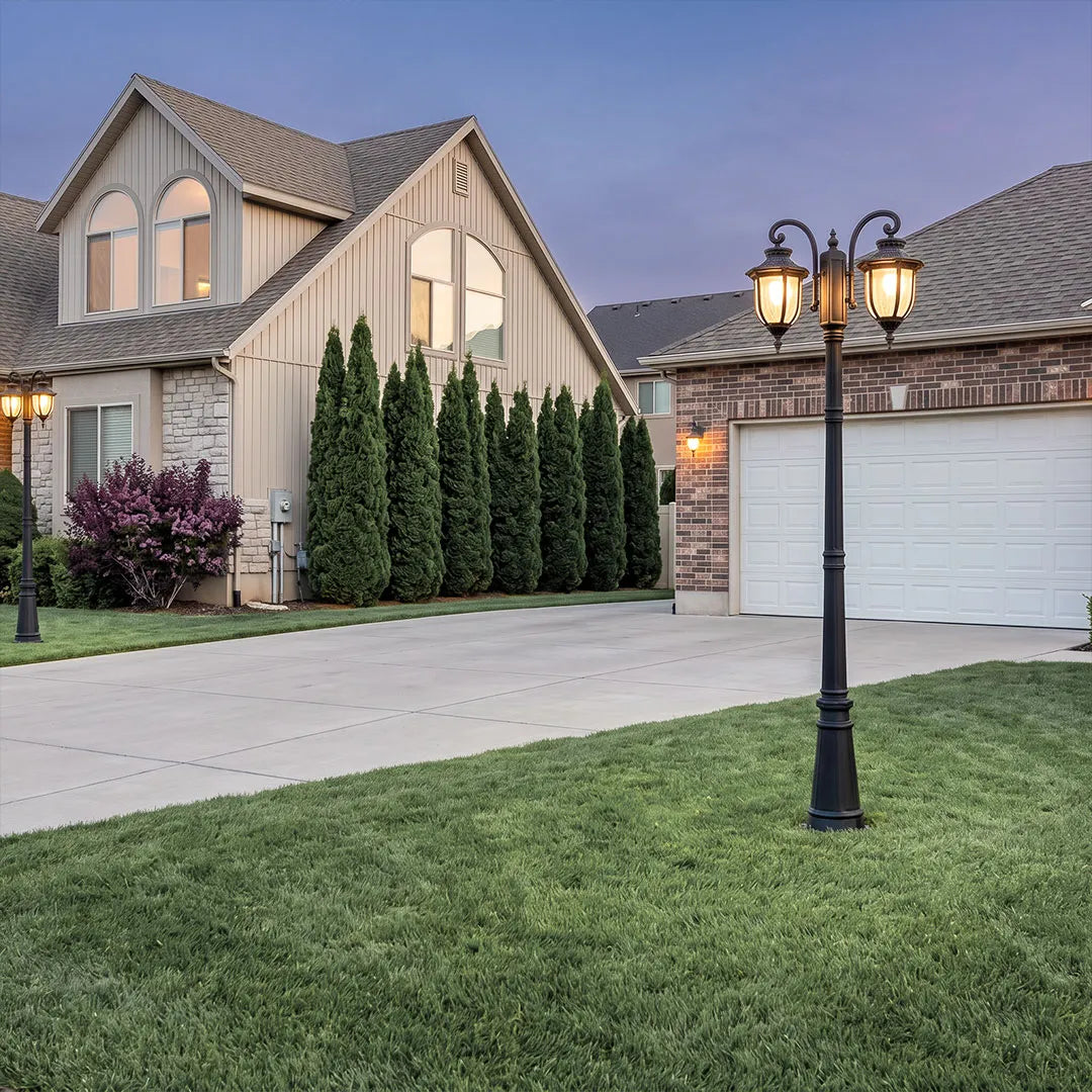 Outdoor post light fixture placed on a front lawn near a driveway and house exterior.