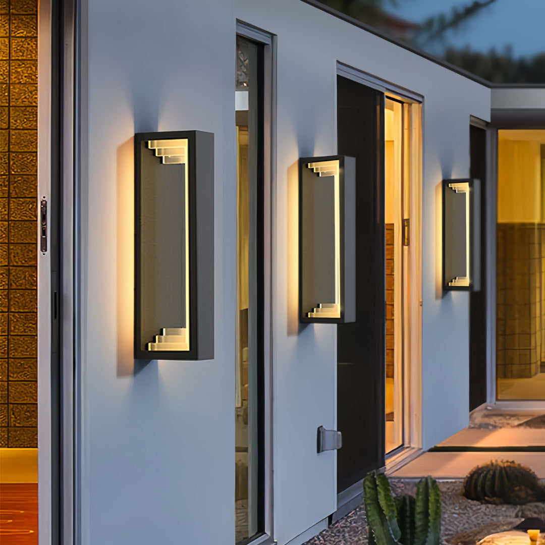 Multiple outdoor sconce modern fixtures mounted on house exterior, creating stylish layered architectural lighting.