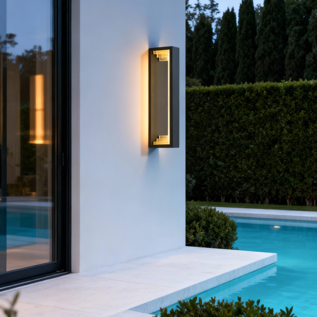 Elegant outdoor sconce modern lighting illuminating a poolside exterior wall with soft warm light.