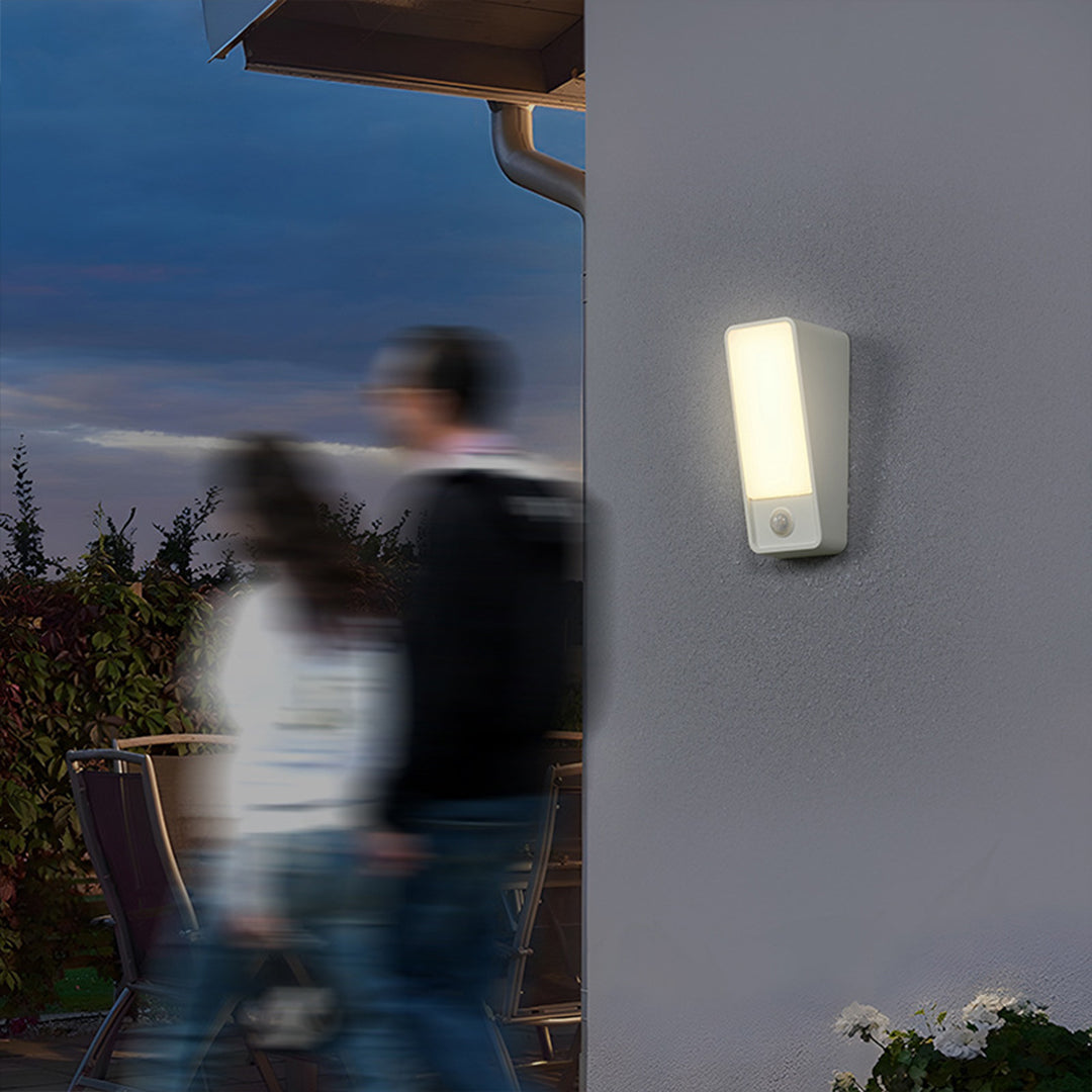 Outdoor security light with motion detection illuminating person walking at twilight