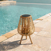 Outdoor solar floor lamps placed beside a swimming pool with a woven rattan shade and tripod base.