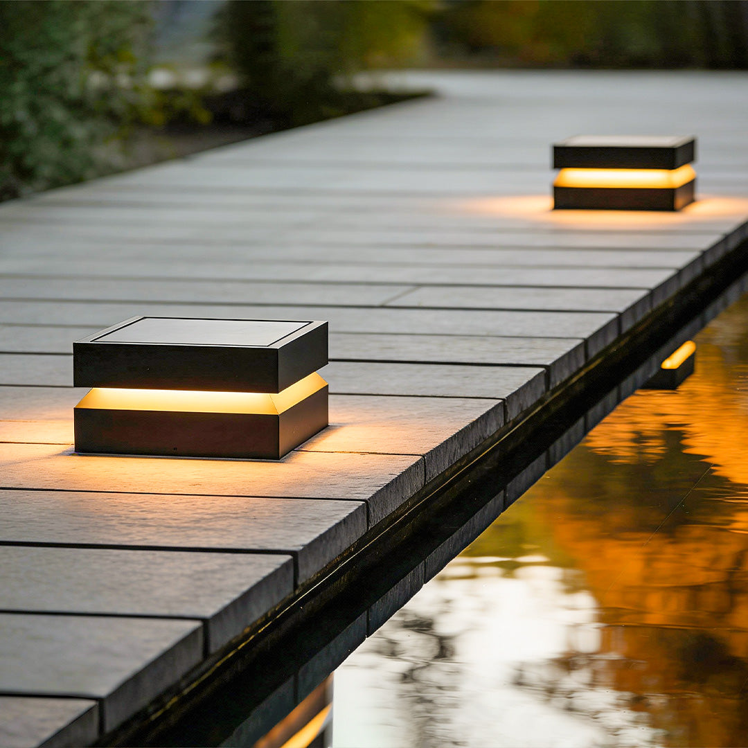Outdoor solar lights deck with modern square design, mounted on wooden pathway beside water.