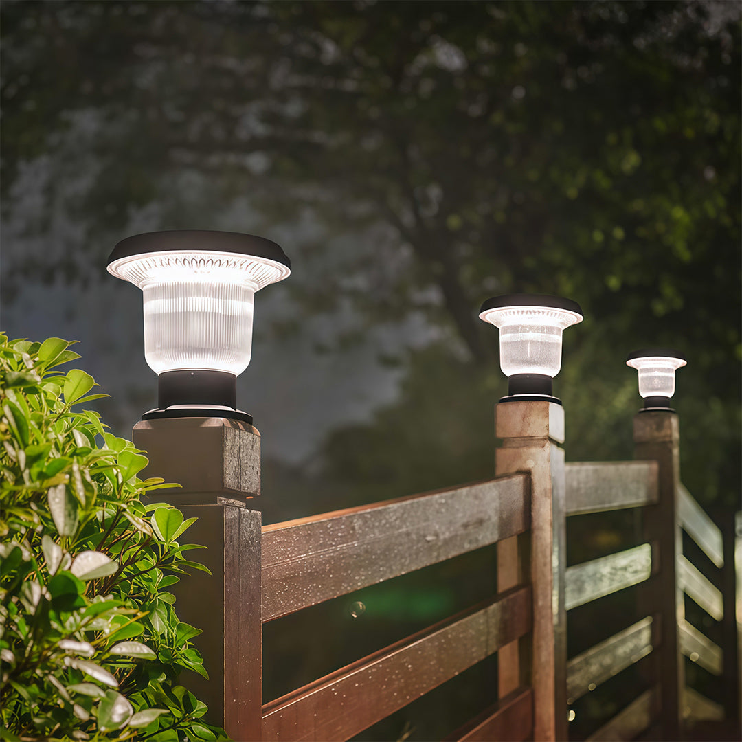 Outdoor solar pillar light placed on a fence pillar, illuminating the garden with soft light.