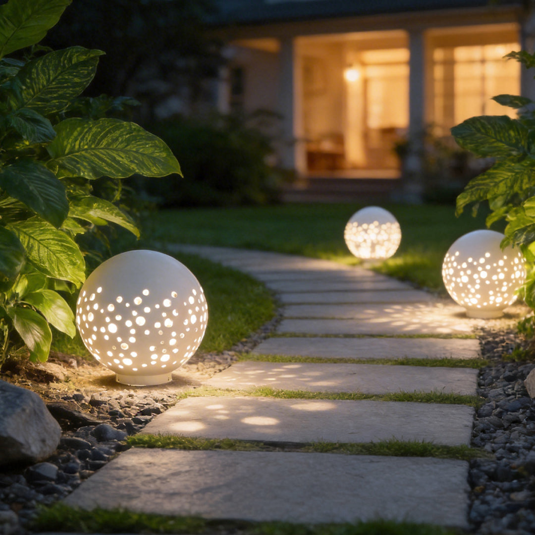 Outdoor sphere light with a white finish, providing soft illumination in a landscaped garden.