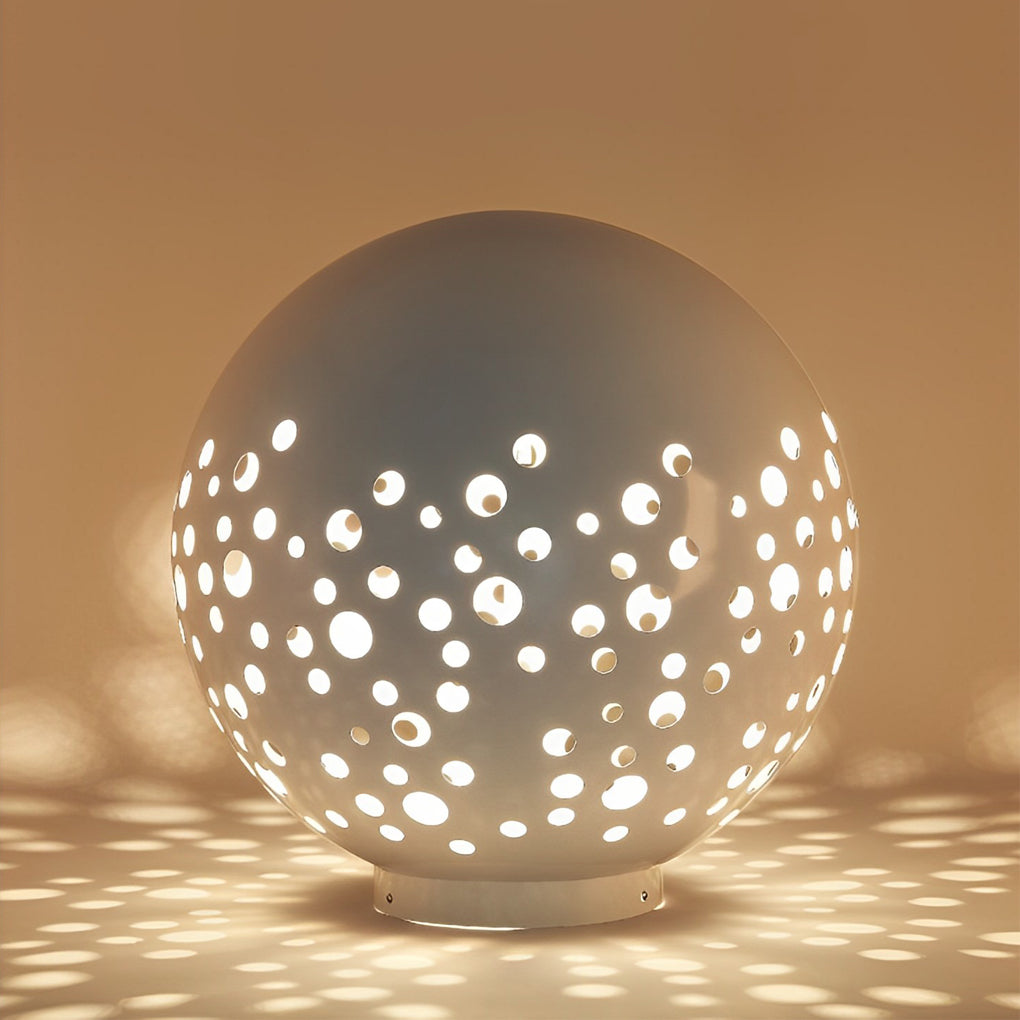 Outdoor sphere light with a white finish, providing warm light near a lawn.