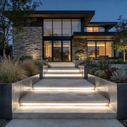 Outdoor stair lighting strips integrated into wide concrete steps leading to a modern landscaped home entrance.