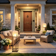 Outdoor standing light illuminating a front patio seating area with a warm frosted globe shade and black frame.