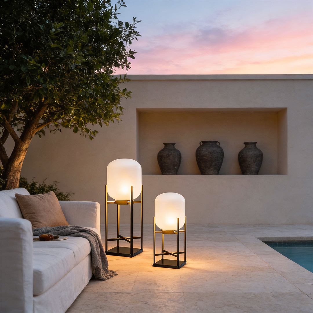 Outdoor standing light illuminating cozy poolside seating area with decorative vases and warm glow.