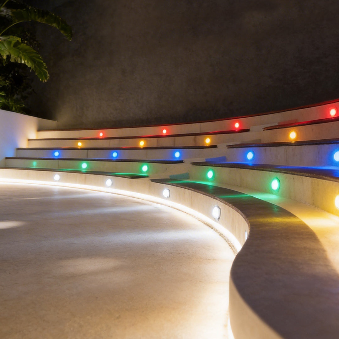 Colorful outdoor step light fixtures embedded in curved stairs, creating a vibrant nighttime effect.