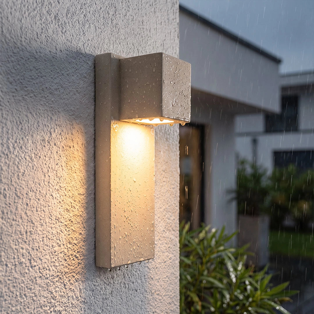 Outdoor stone wall lighting in a light stone finish shown in close-up with a warm downward glow.