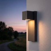 Outdoor stone wall lighting in a dark gray finish mounted on an exterior wall at dusk.