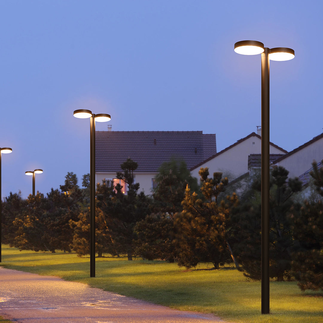 A series of outdoor street lights illuminating a well-paved road at night.