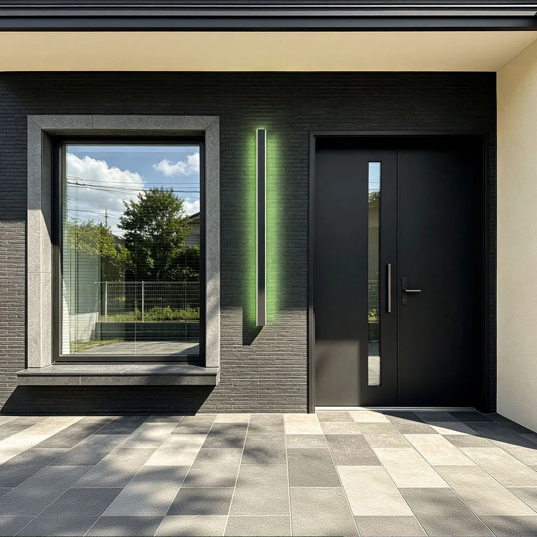 Outdoor strip wall light mounted beside a modern front door on a dark stone exterior wall.
