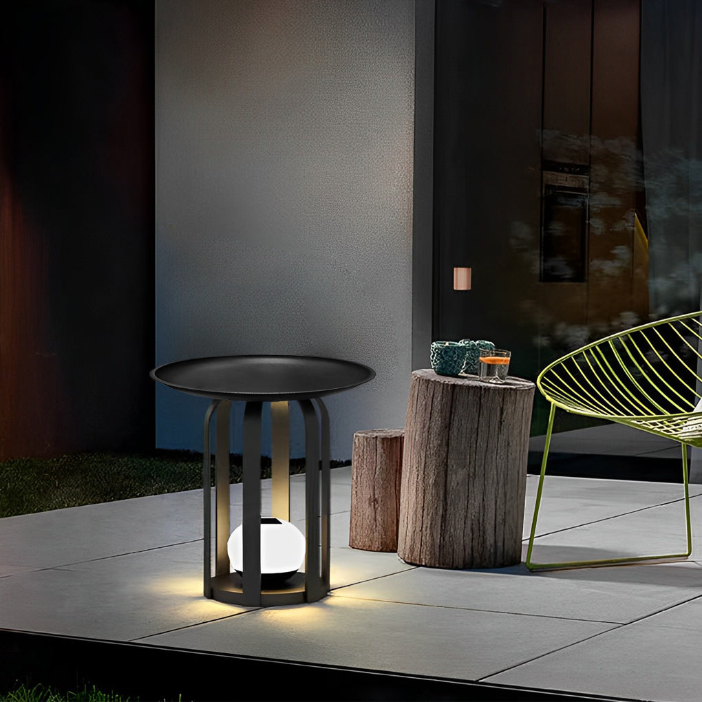 Outdoor tray floor lamp with a black metal frame, providing soft illumination in a garden.
