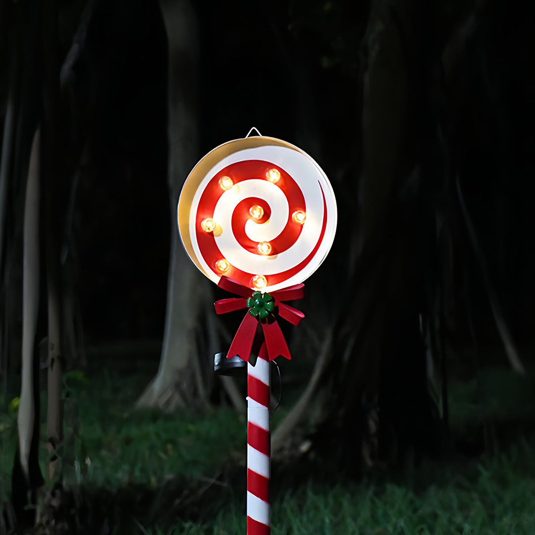 Illuminated Christmas tree ground stake for Christmas lights placed outdoors in snowy holiday scenery.